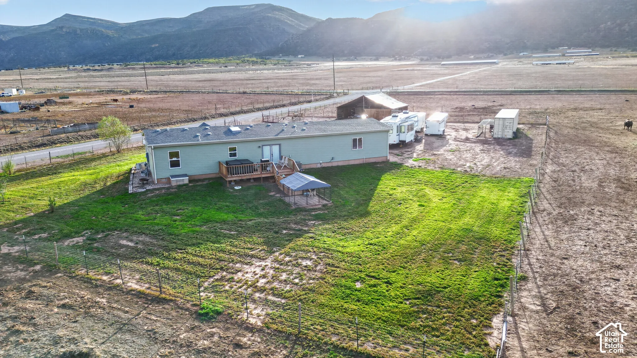 Expansive open land with a residential structure, detached barn, and visible mountainous backdrop