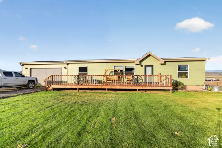 Siding exterior with multiple windows, a prominent wood deck, and an attached garage