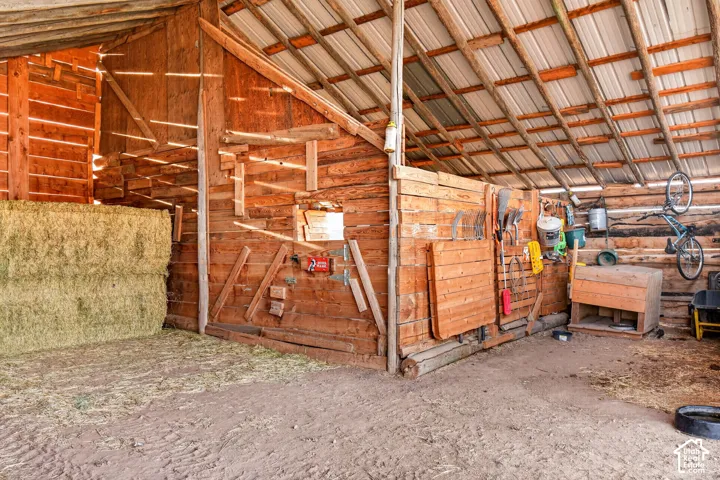 Barn interior featuring wood plank construction, exposed support beams, and a metal roof