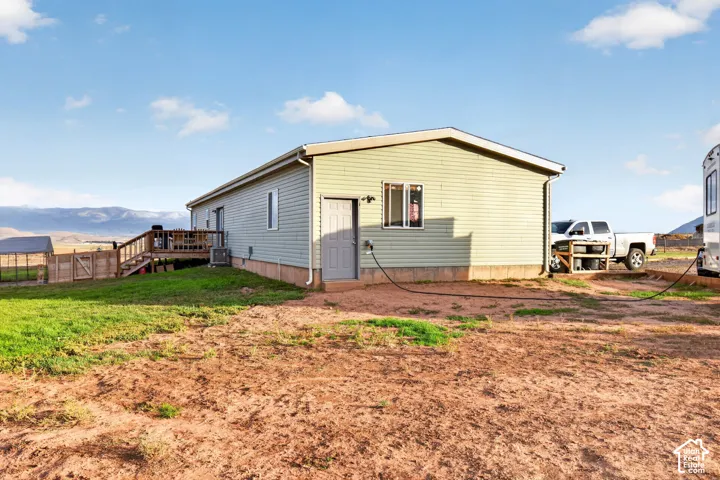 Light green siding exterior, rear wooden deck, concrete foundation, and a metal rain gutter system