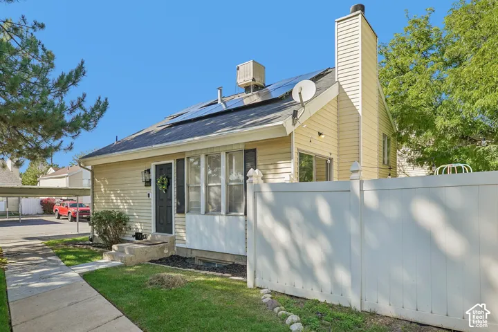 Exterior with light-toned siding, a dark front door, and a white privacy fence