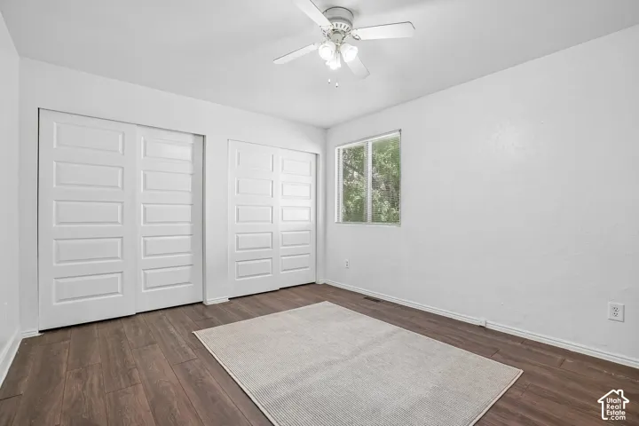Wood-finish flooring, white walls, and a ceiling fan with light fixture