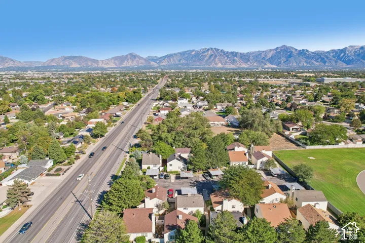 Aerial perspective showcasing suburban development with residential structures, mature trees, and mountainous backdrop