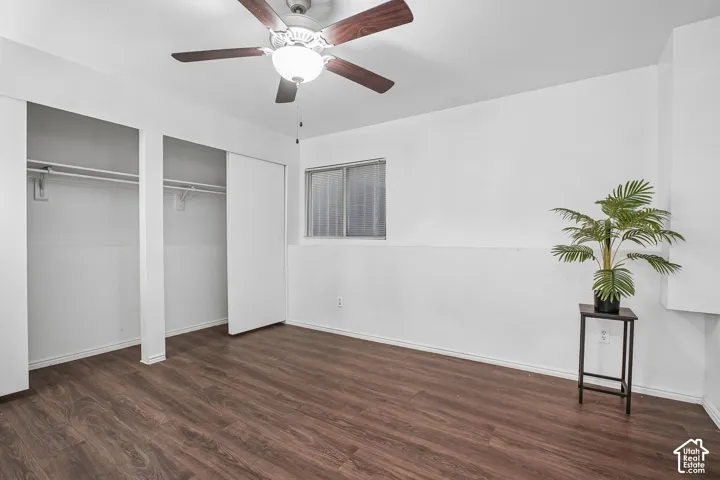 Wood-finish flooring, ceiling fan with integrated lighting, sliding closet doors, and a window