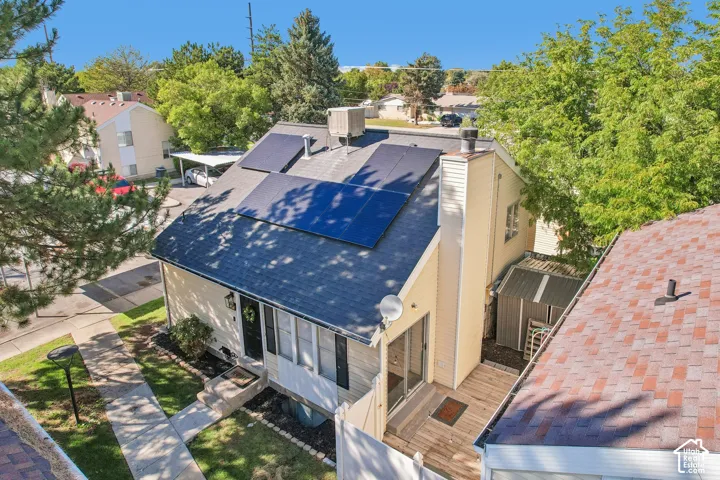 Pitched roof with installed solar panels, siding exterior, front entry with porch, and a rear deck with an adjacent storage shed
