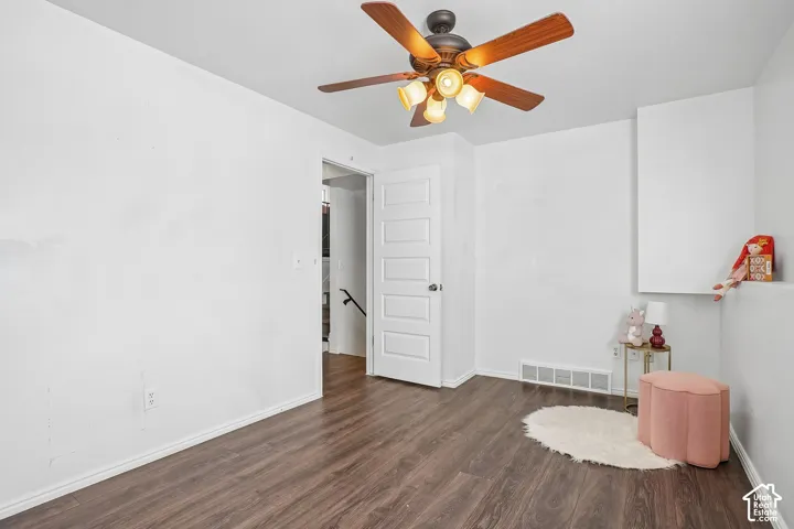 Wood-finish flooring, white walls, and a ceiling fan with integrated lighting
