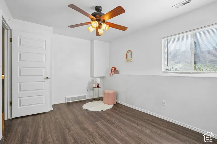 Wood-finish flooring, white paneled door, ceiling fan with integrated lighting, and a large window with blinds