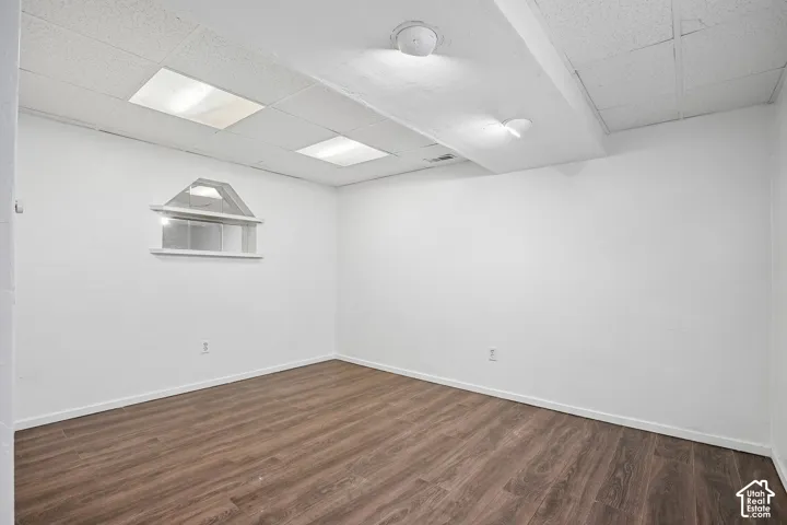 Wood-finish flooring with white baseboards and painted white walls