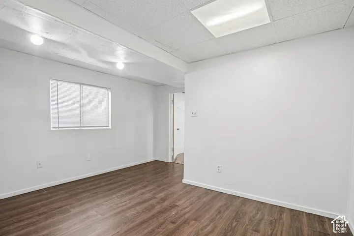 Wood-finish flooring, white painted walls, and a window with blinds