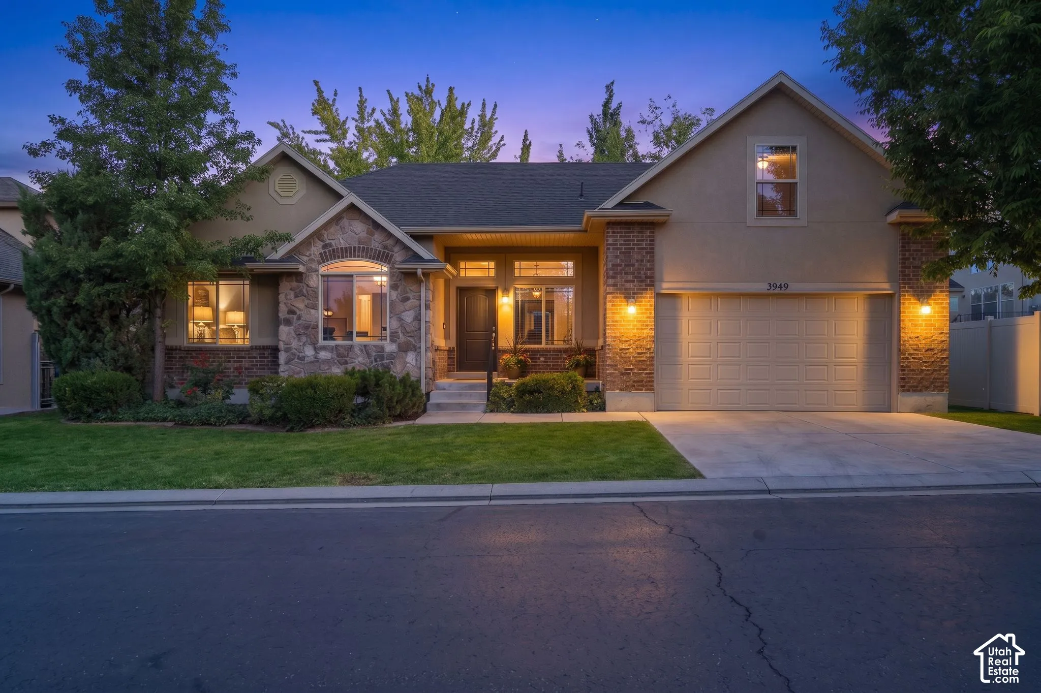 Stucco exterior with stone accents, an attached two-car garage, and a concrete driveway