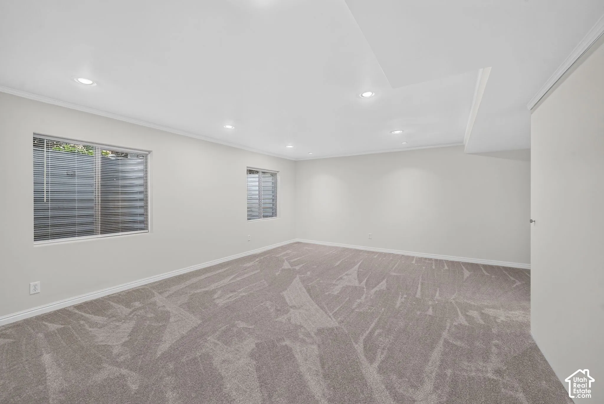 Spacious room with recessed lighting, light gray carpeting, dual windows, and crown molding