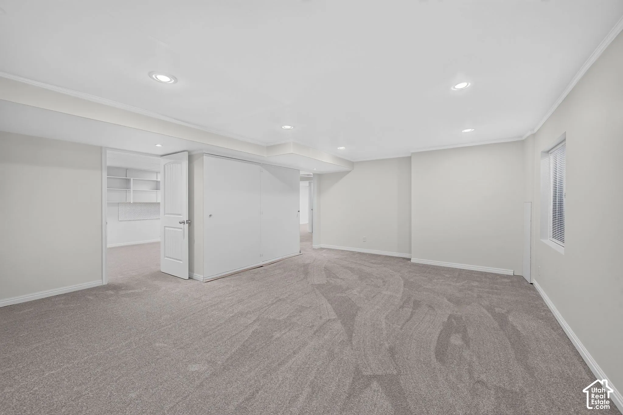 Expansive room with recessed lighting, light-toned walls, and grey patterned carpeting