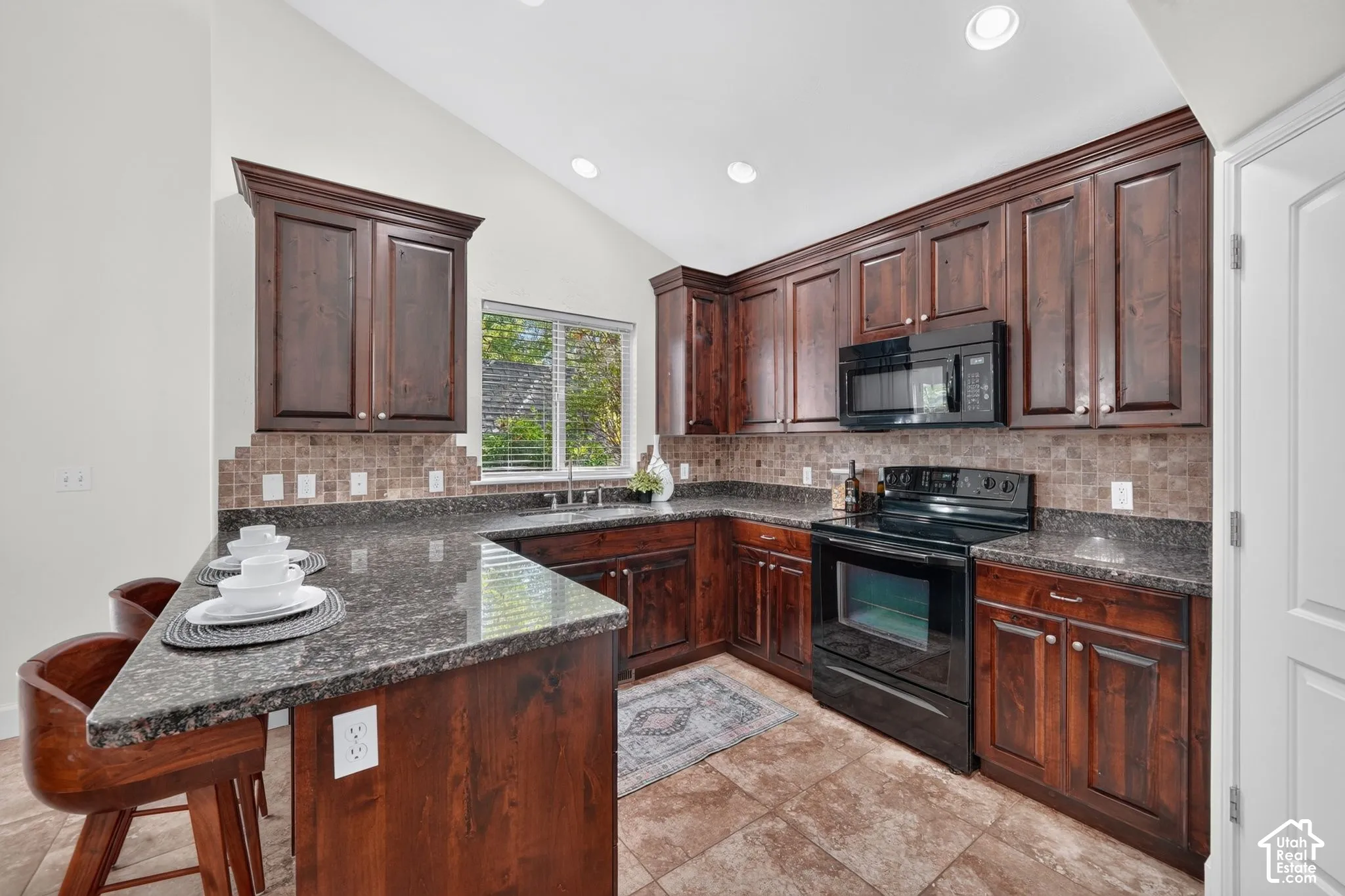 Kitchen featuring dark wood cabinetry, a built-in microwave, an electric range, granite countertops, and tile flooring