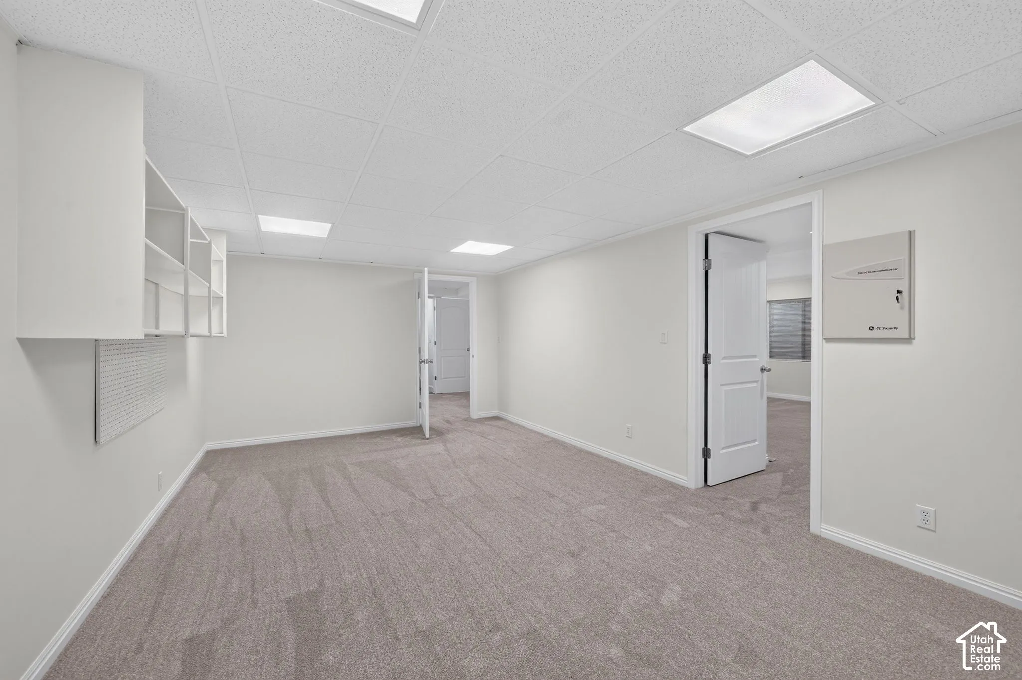 Recessed lighting, light-toned carpet, built-in shelving, white trim, and a drop ceiling