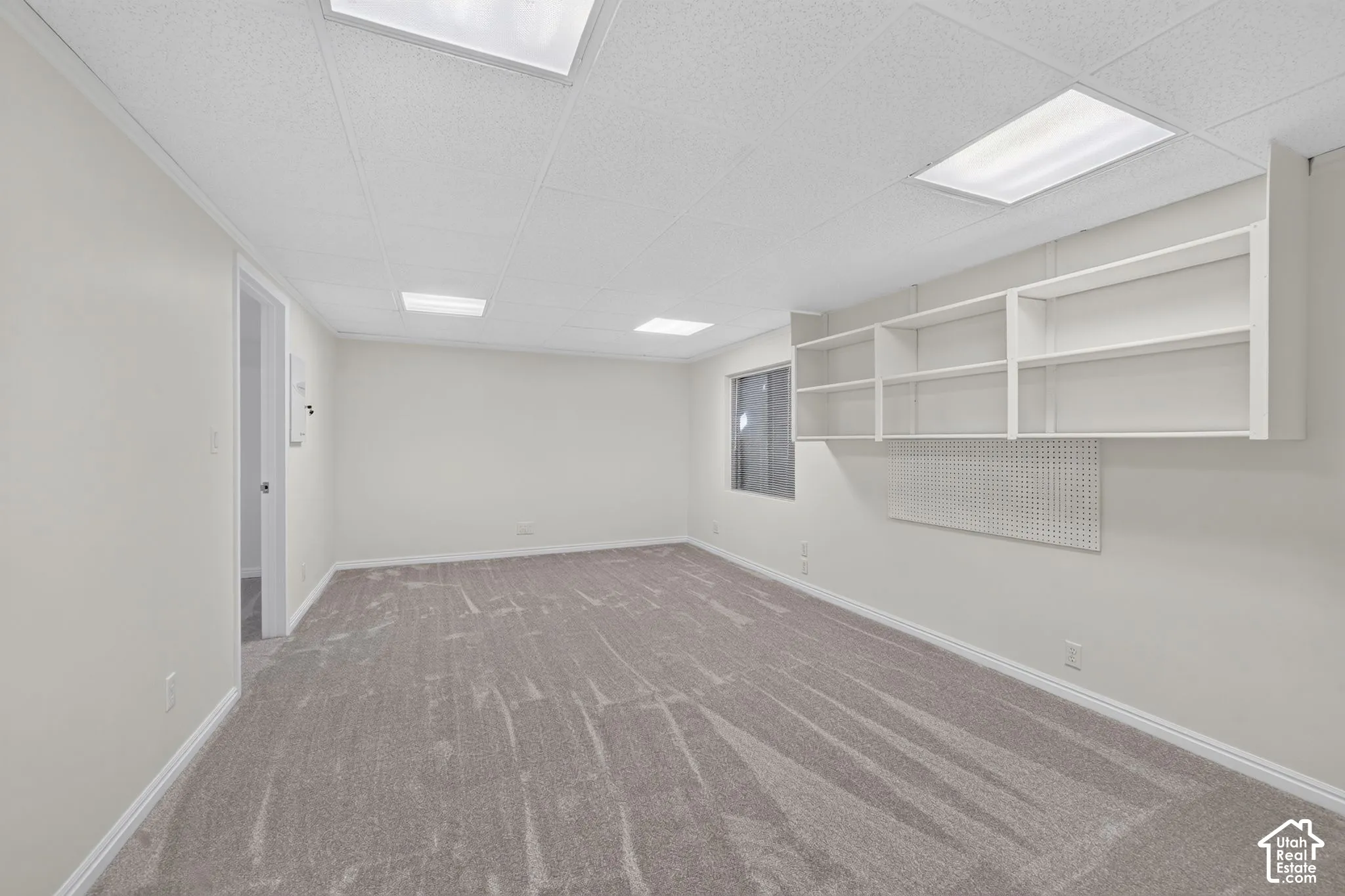 Spacious room with gray carpet, white walls, built-in shelving, and recessed lighting