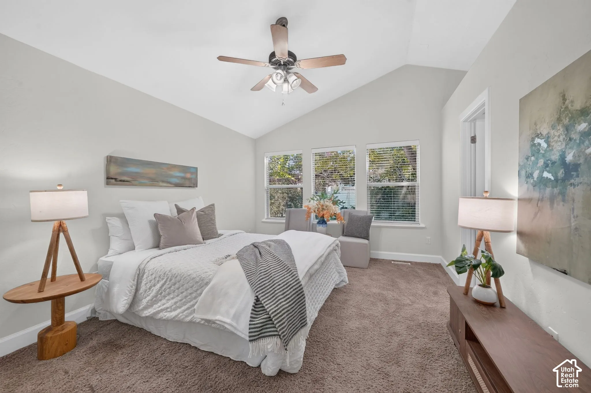 Vaulted ceiling with a ceiling fan, multiple windows, wall-to-wall carpeting, and white trim molding
