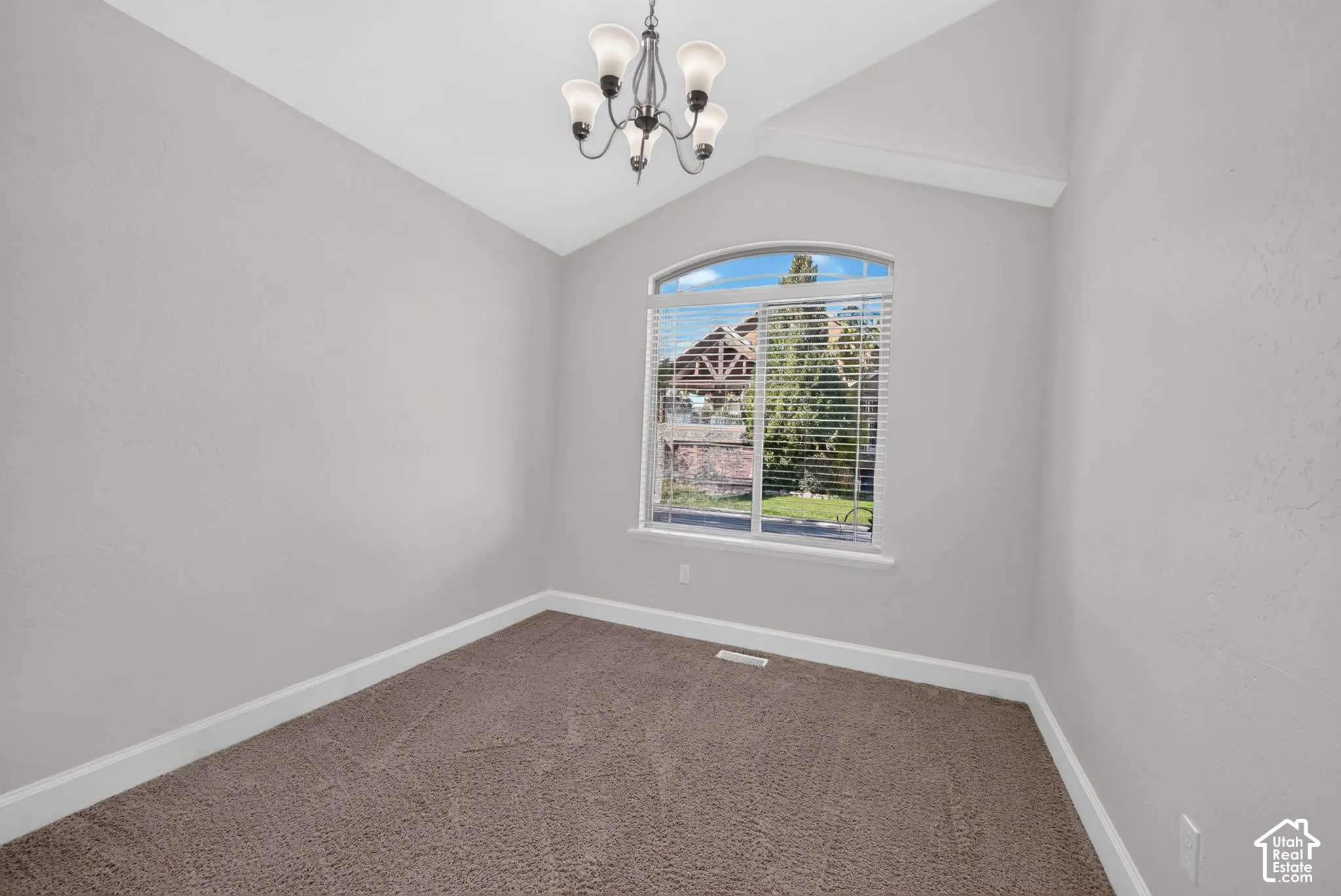 Arched window with blinds, vaulted ceiling, recessed lighting, and neutral-toned carpeting
