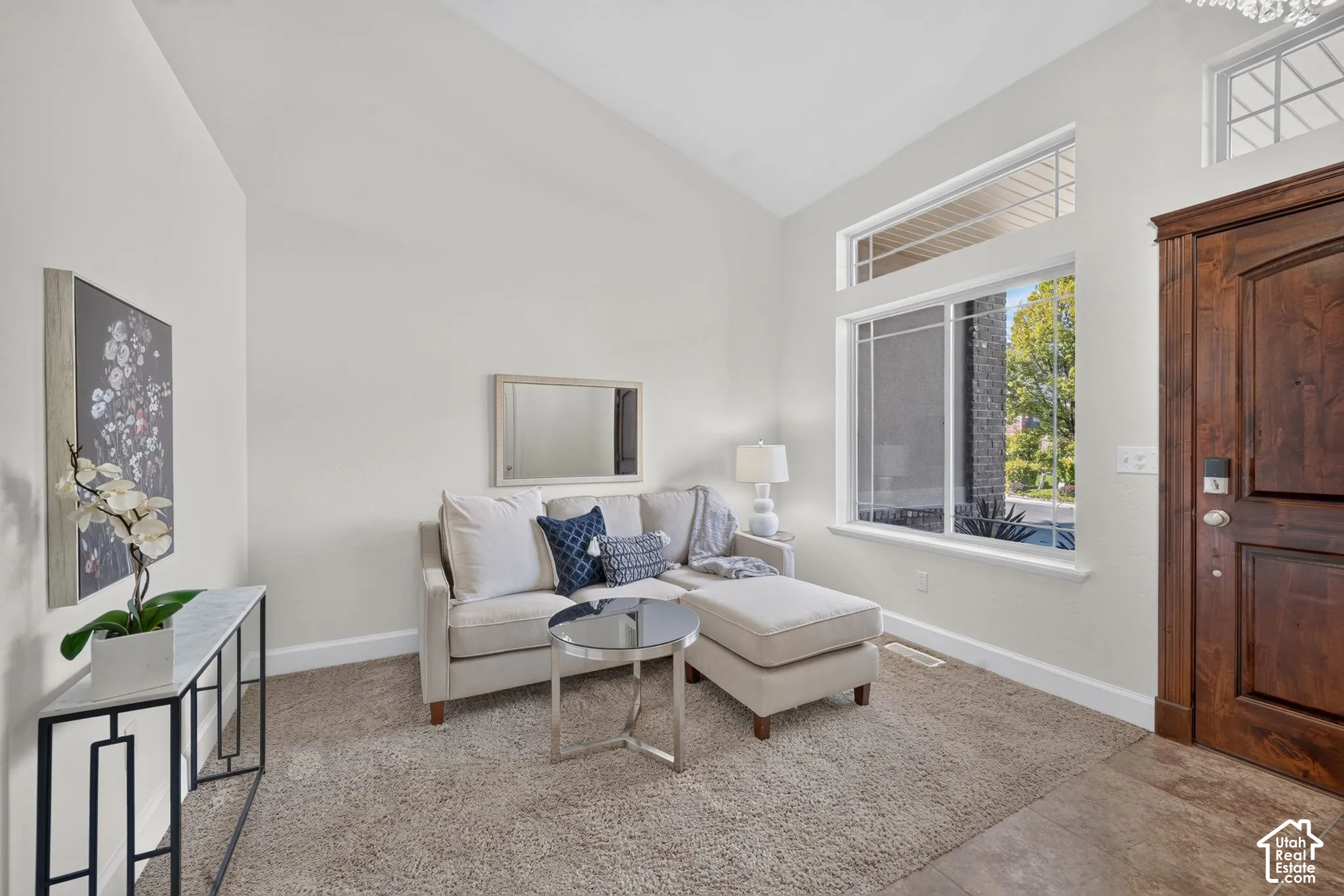 Vaulted ceiling, transom windows, wood-finish entryway door, large window, and carpeted flooring