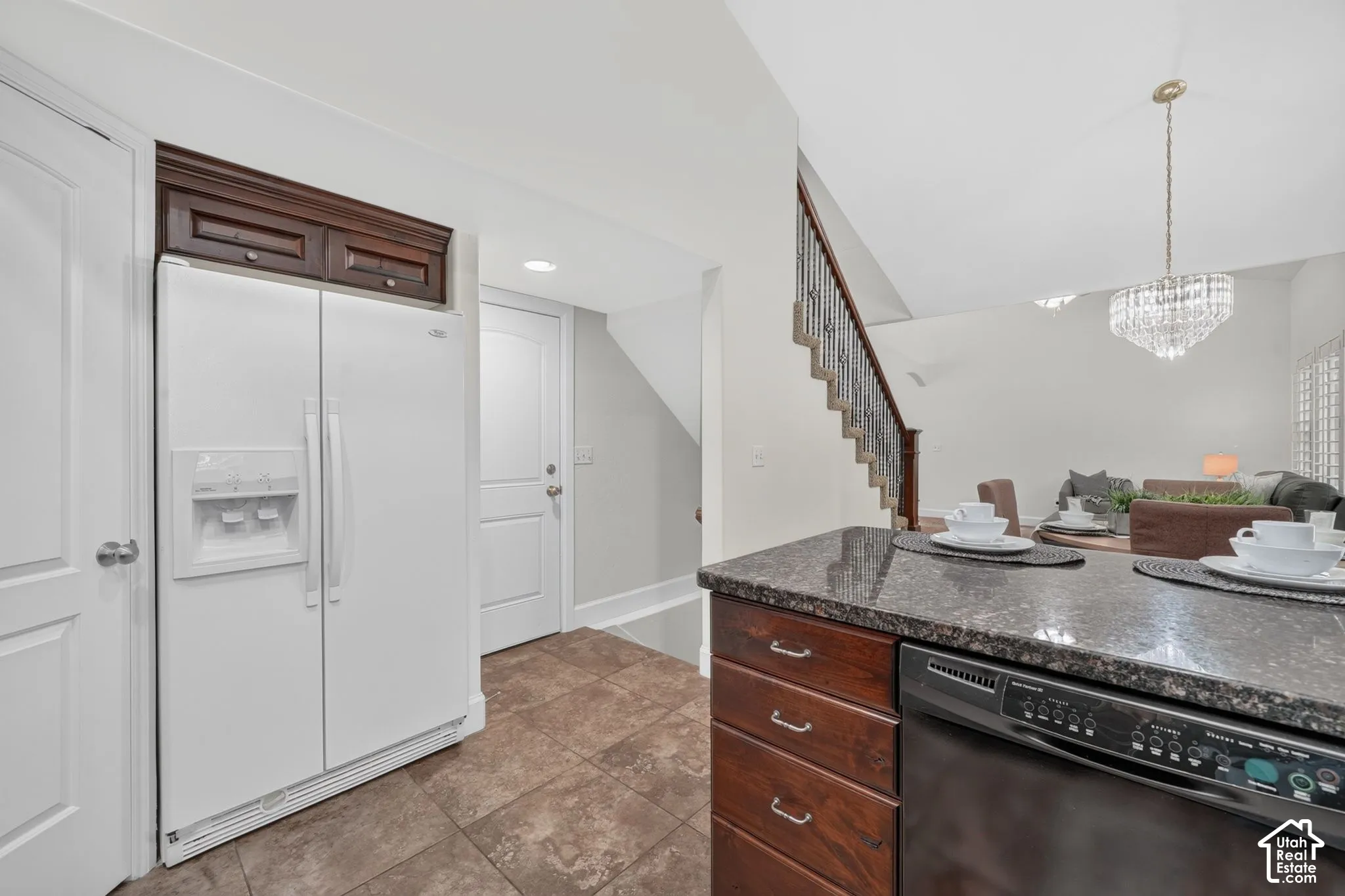 Kitchen island with a dark granite countertop, wood-finish cabinetry, and an integrated dishwasher