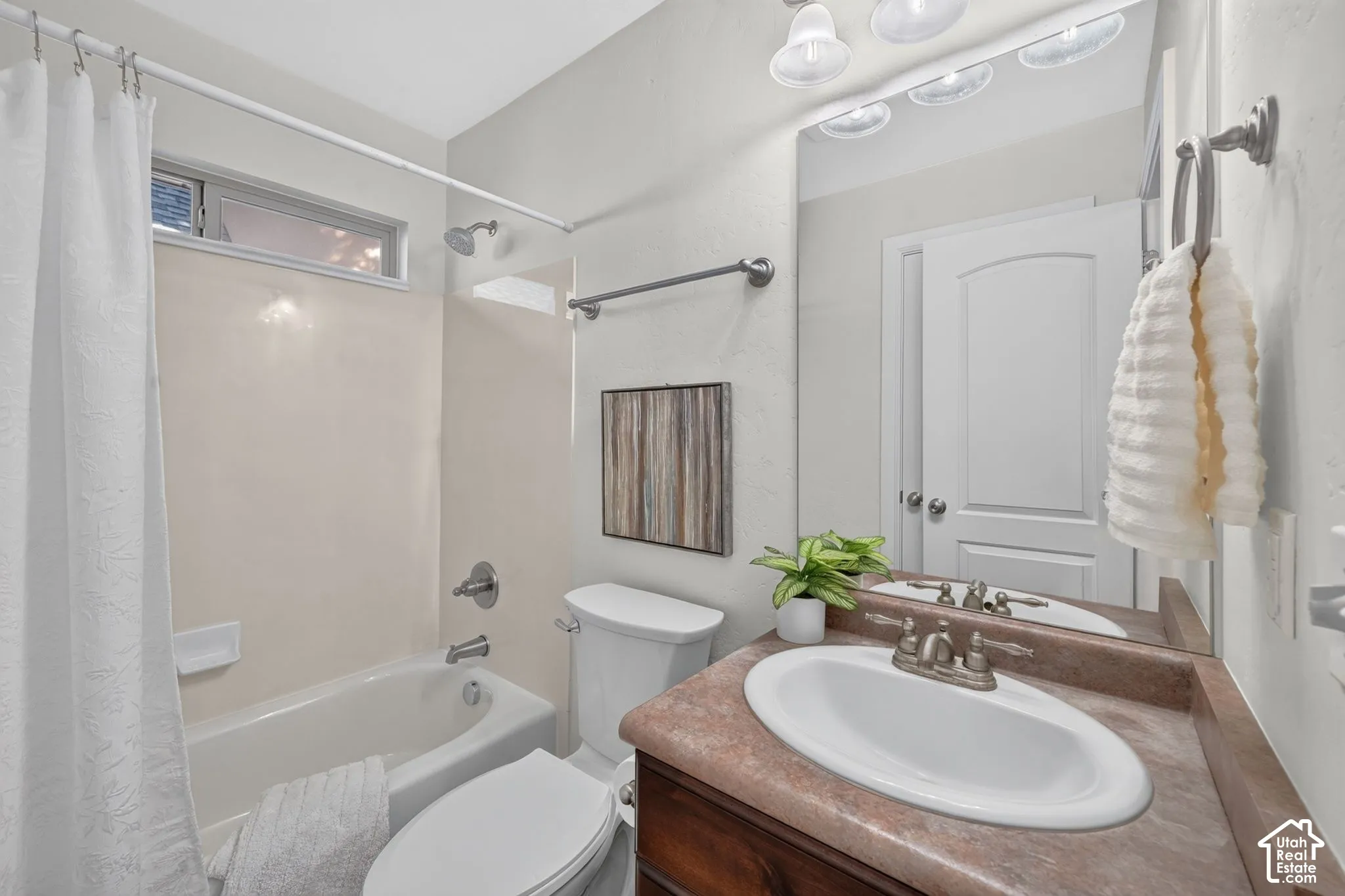 Bathroom featuring a single vanity with an integrated sink, an overhead light fixture, a mirrored medicine cabinet, a full-size bathtub, and a toilet