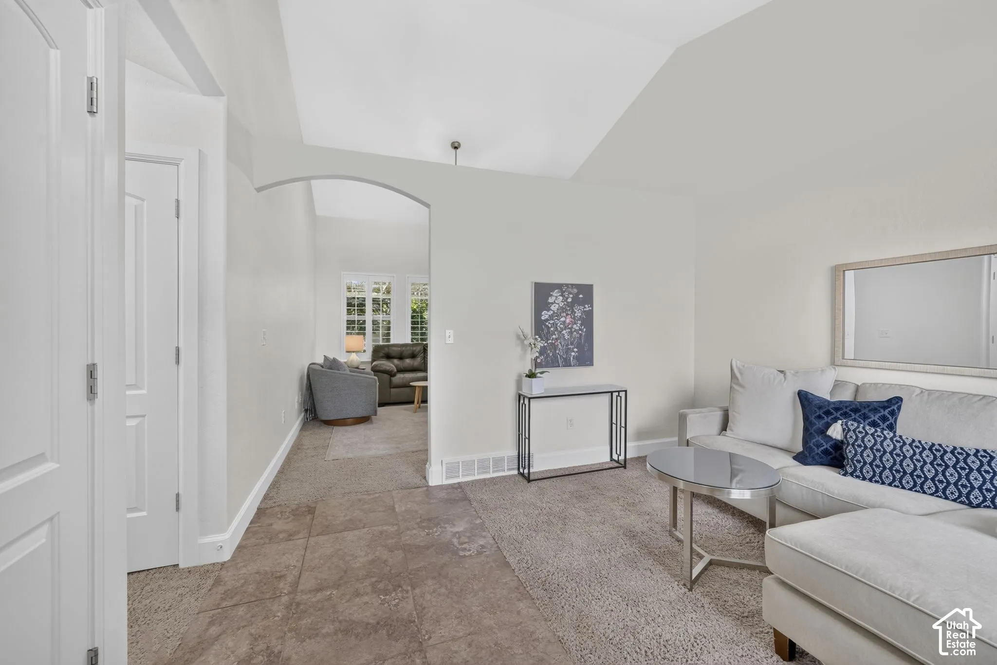 Vaulted ceiling, arched doorway, panel doors, carpeted flooring, and tiled entryway