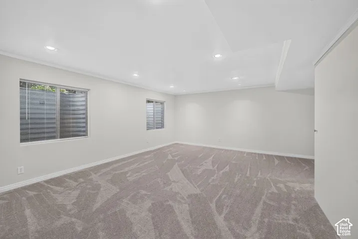 Spacious room with recessed lighting, light gray carpeting, dual windows, and crown molding