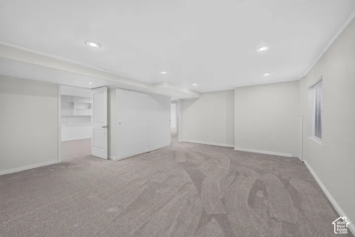 Expansive room with recessed lighting, light-toned walls, and grey patterned carpeting