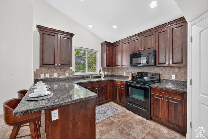 Kitchen featuring dark wood cabinetry, a built-in microwave, an electric range, granite countertops, and tile flooring