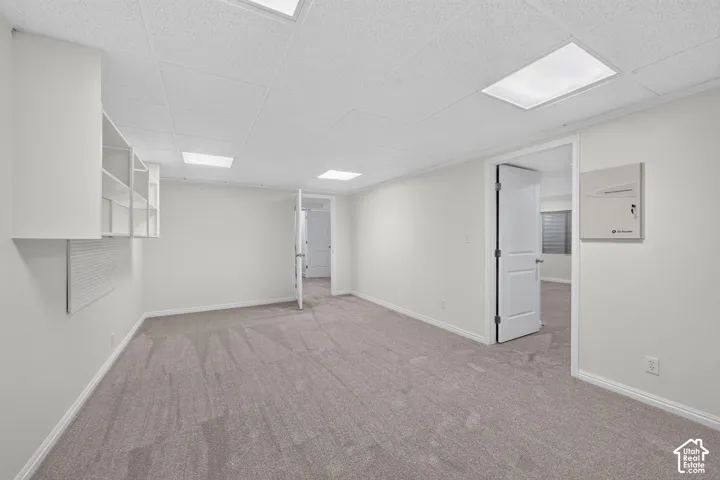 Recessed lighting, light-toned carpet, built-in shelving, white trim, and a drop ceiling