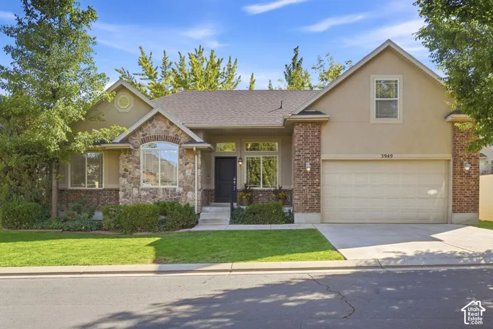 Stucco and stone exterior with brick accents, an arched window, and an attached garage