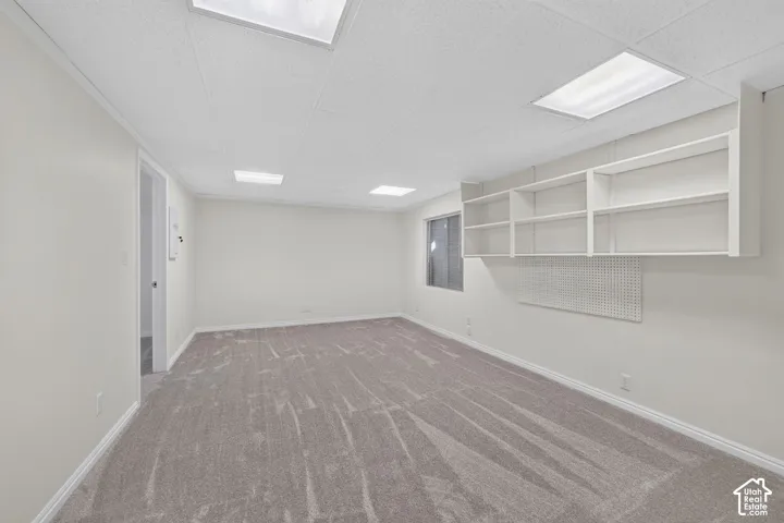 Spacious room with gray carpet, white walls, built-in shelving, and recessed lighting
