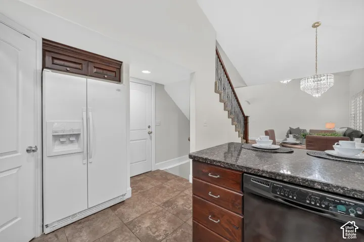 Kitchen island with a dark granite countertop, wood-finish cabinetry, and an integrated dishwasher