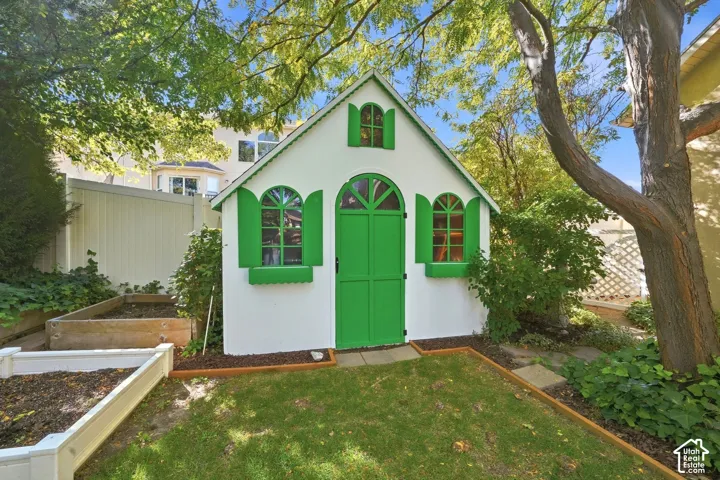 Gable-roof storage shed with arched windows and double doors, featuring green accents