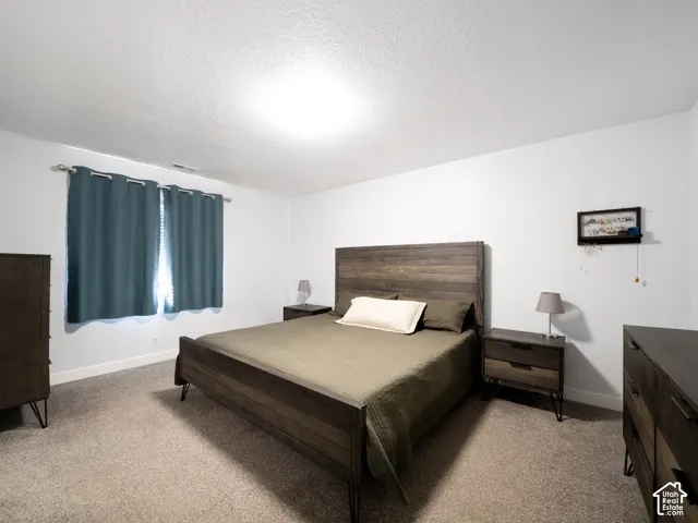 Recessed window with curtain rod and drapes, wall-to-wall carpeting, and bright overhead lighting