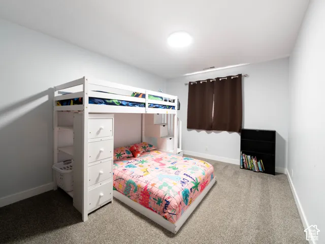 Light gray walls, light gray carpet flooring, window with brown curtain, and ceiling-mounted light fixture