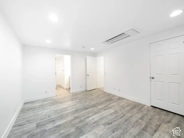 Light gray wood-finish flooring, recessed ceiling lighting, and crisp white walls