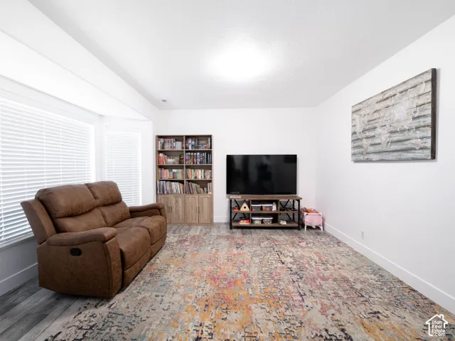 Bay window with blinds, wood-finish flooring, recessed lighting, and white walls