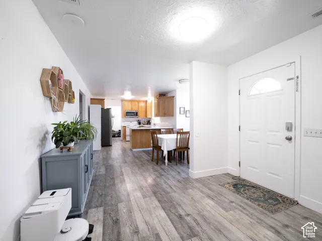 Wood-finish flooring throughout, white walls, and a white front door with an arched window