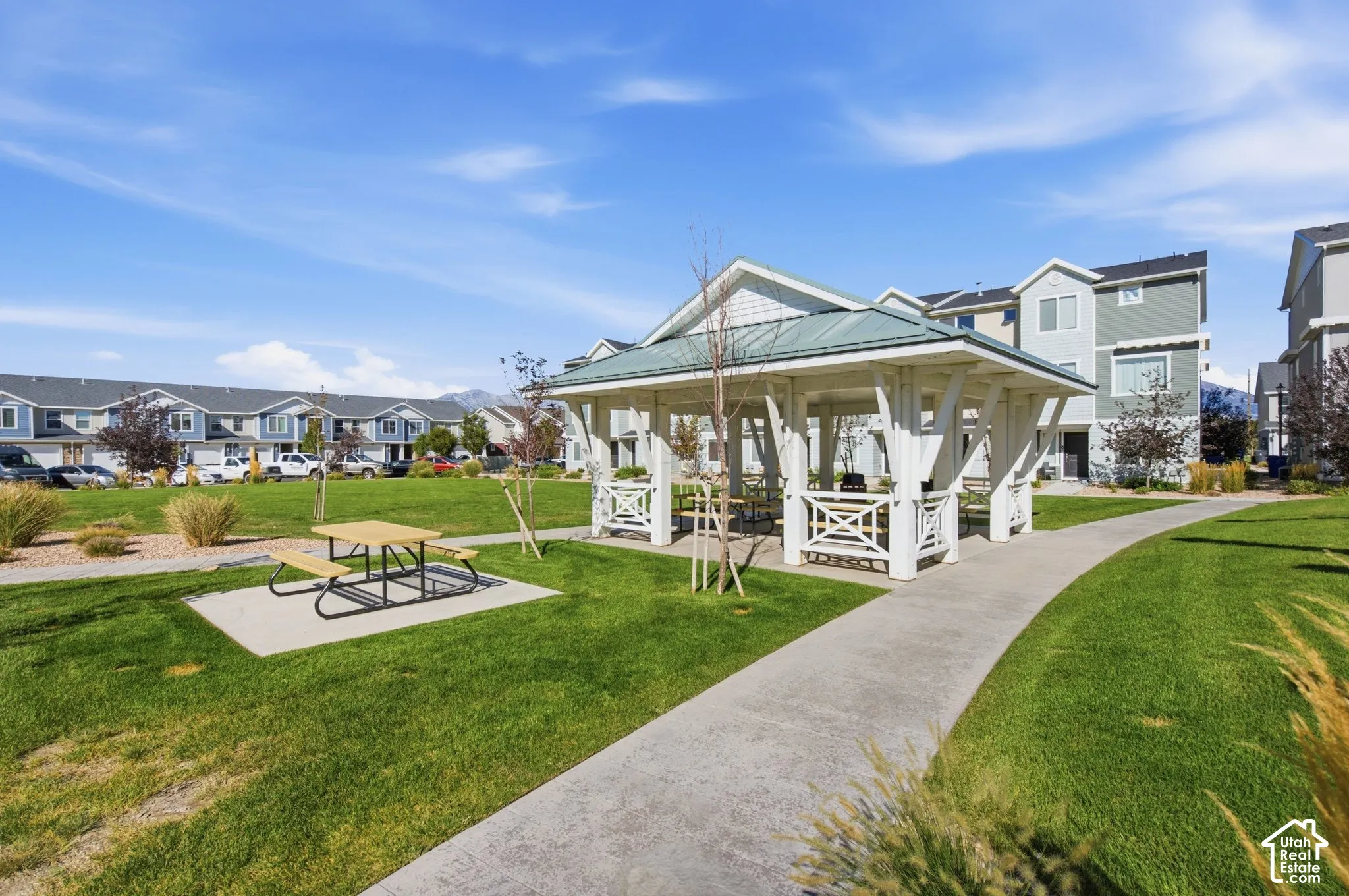 Expansive green space featuring a white gazebo, concrete pathways, and a picnic area