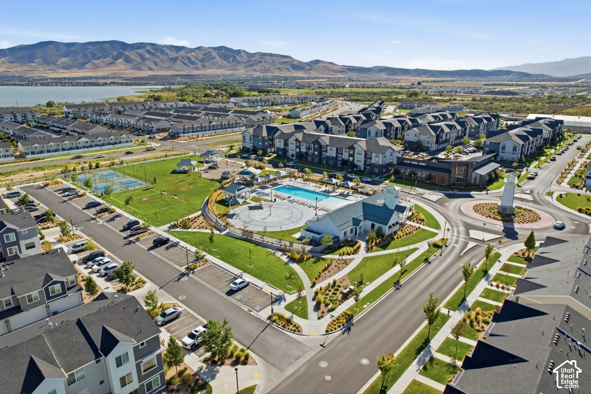 Community pool, landscaped grounds, tennis courts, mountain backdrop, and lake access