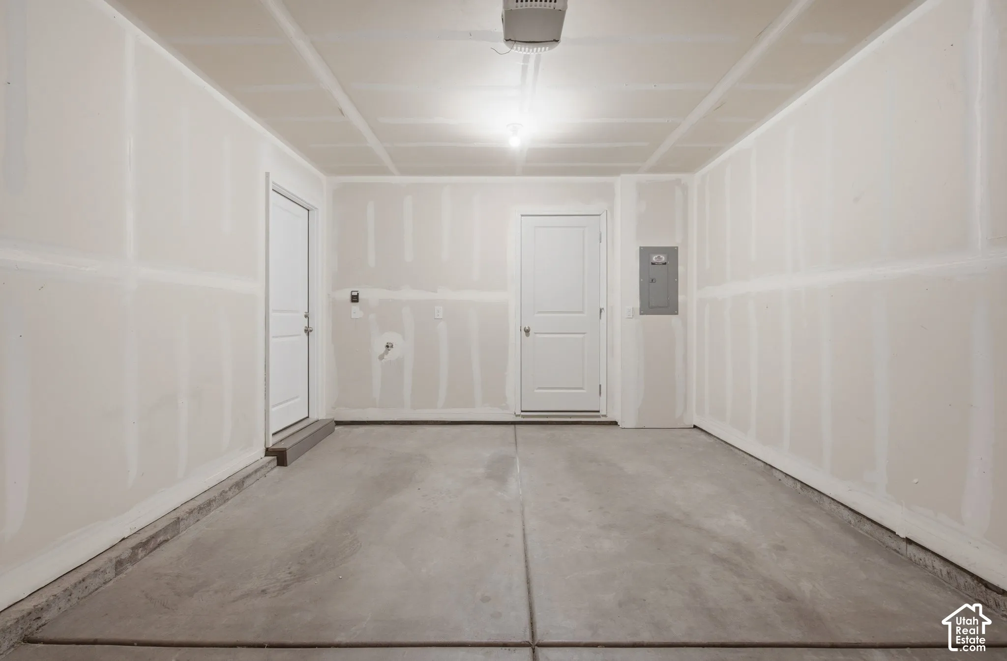 Concrete floor, two panel doors, electrical panel, overhead lighting