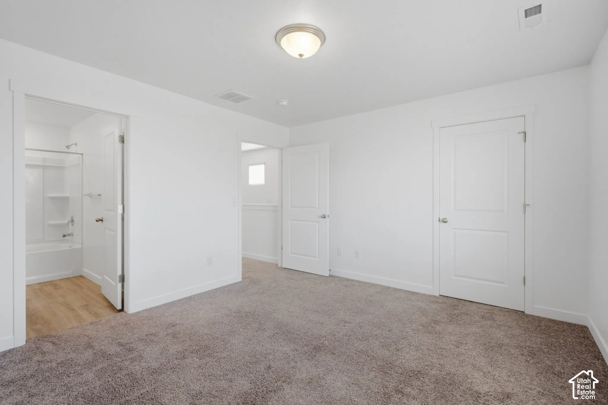 Neutral wall color, carpeted flooring, overhead lighting fixture, shaker-style interior doors, and a full bathroom with a tub/shower combination and wood-finish flooring