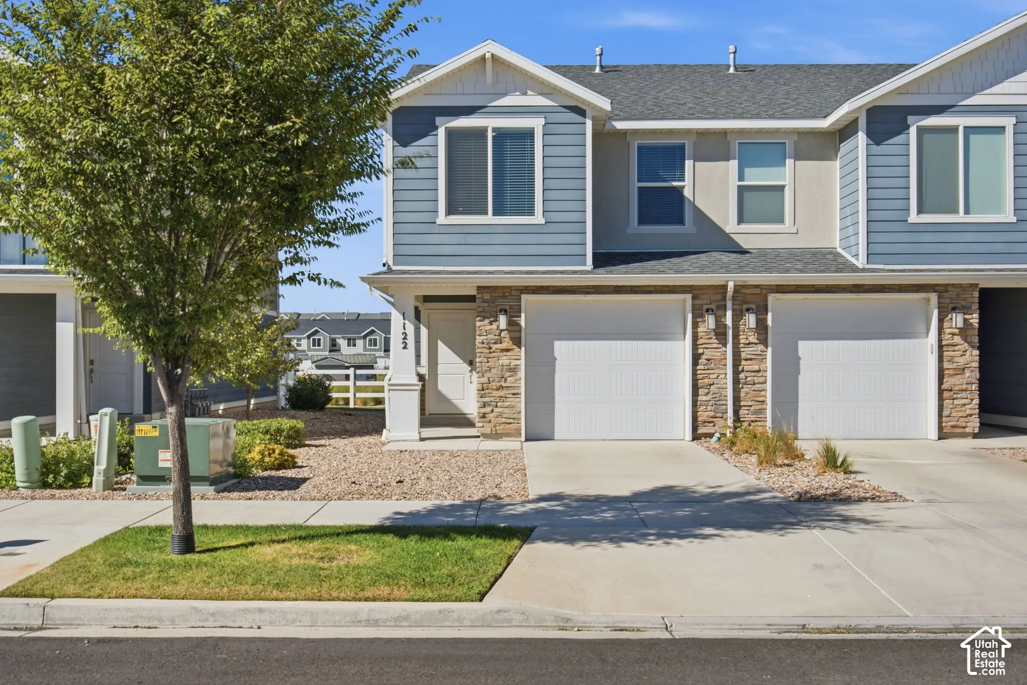 Two-story townhouse with blue siding, stone facade accents, and a dual-car garage