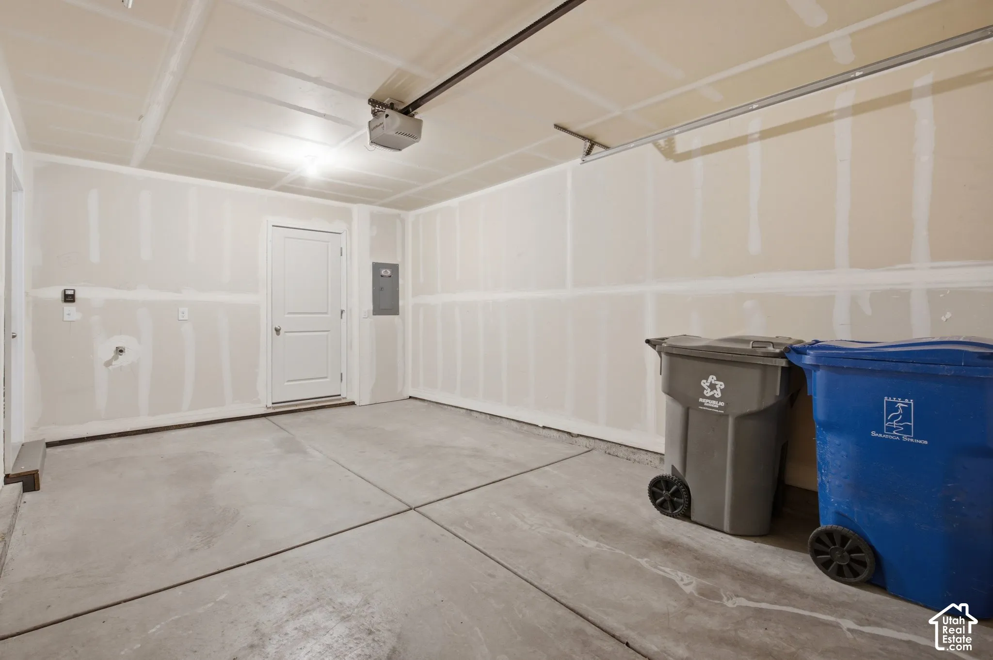 Concrete flooring with expansion joints, overhead lighting, and an overhead door opener mechanism