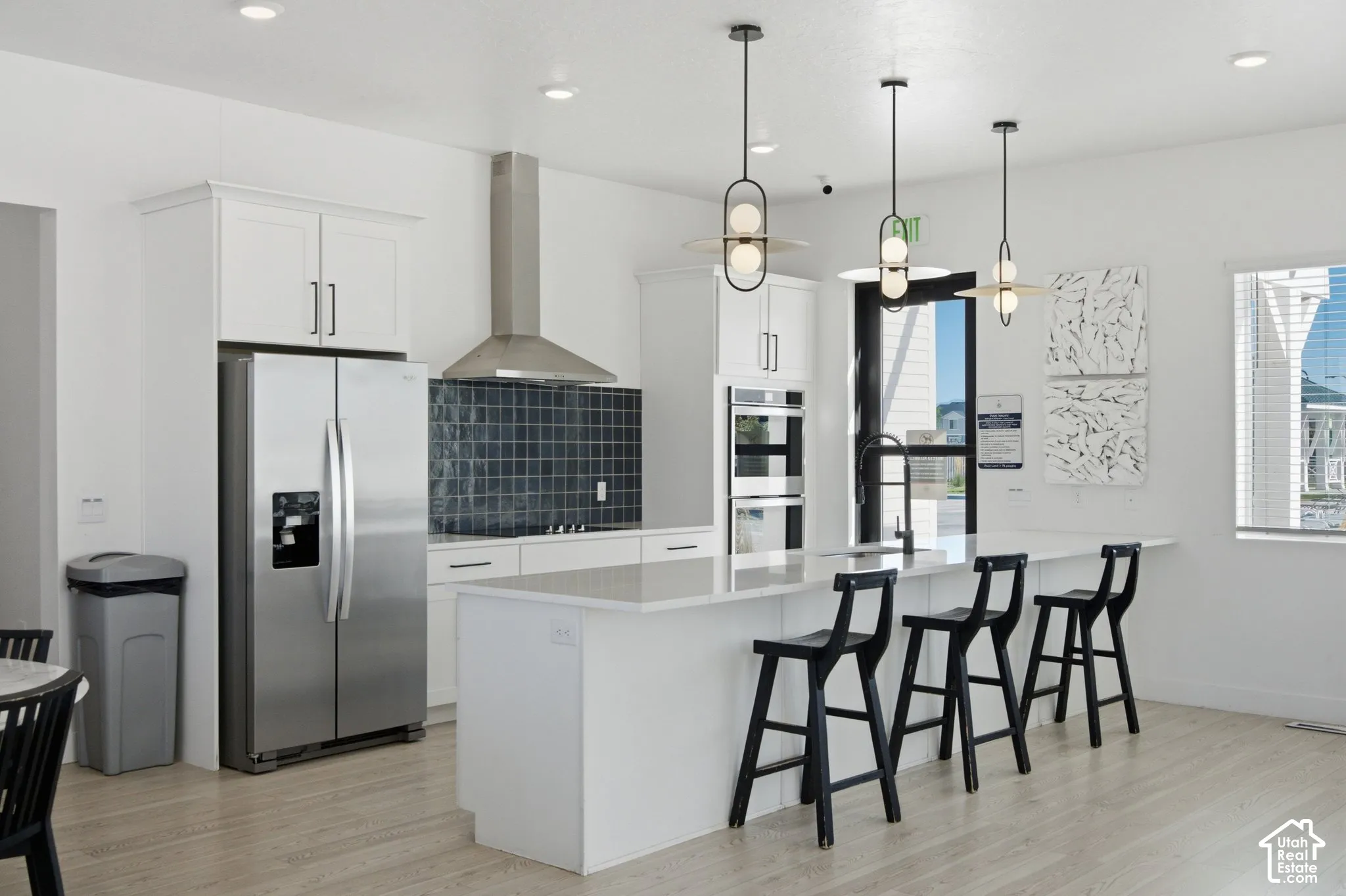 Kitchen featuring stainless steel appliances, white cabinetry, a large kitchen island, and contemporary pendant lighting