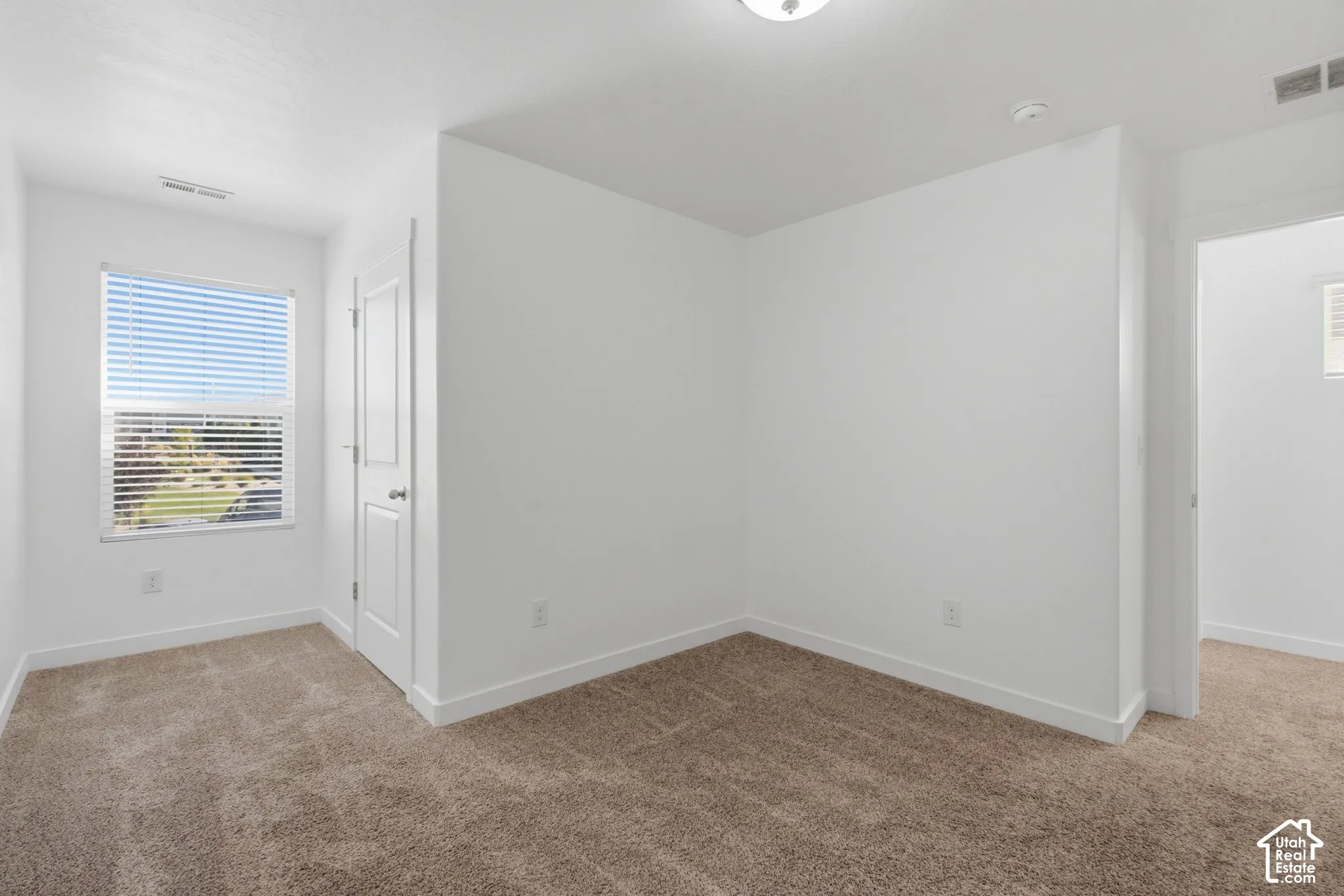 Carpeted flooring, white walls, window with blinds, and white trim