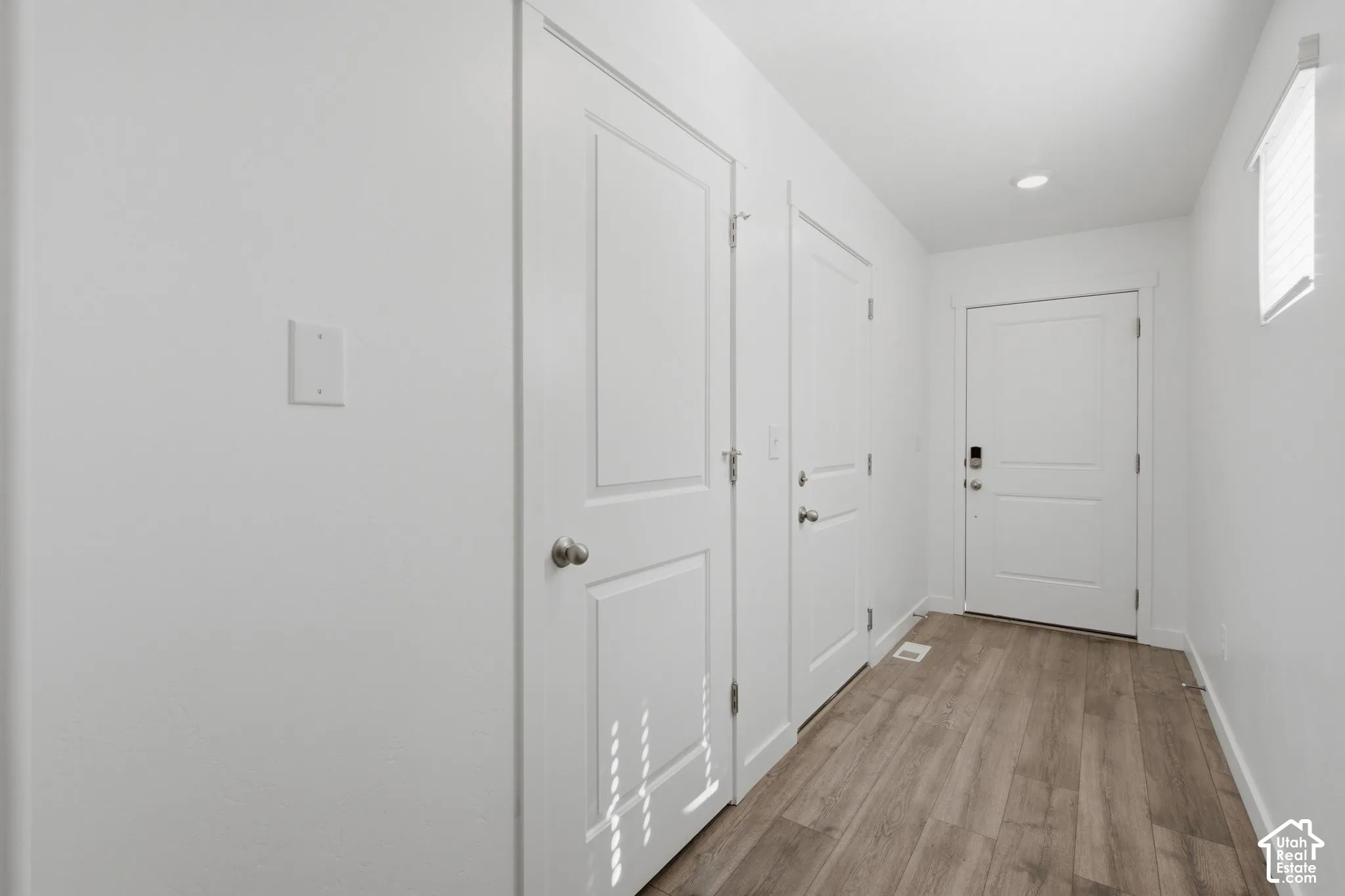 Wood-finish flooring, white walls, and recessed lighting
