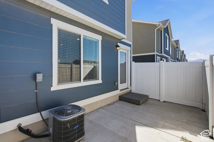 Private fenced patio with a concrete surface, featuring a rear entry door and a white vinyl fence