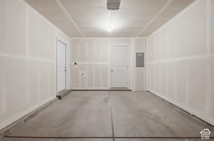 Concrete floor, two panel doors, electrical panel, overhead lighting