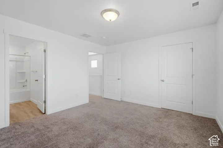 Neutral wall color, carpeted flooring, overhead lighting fixture, shaker-style interior doors, and a full bathroom with a tub/shower combination and wood-finish flooring